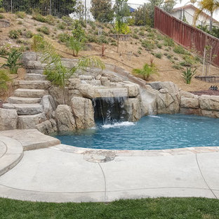 Esempio di una piscina tropicale a "C" di medie dimensioni e dietro casa con pavimentazioni in pietra naturale