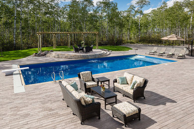 Diseño de piscina alargada tradicional renovada extra grande rectangular en patio trasero con losas de hormigón