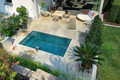 Ejemplo de piscina elevada contemporánea pequeña rectangular en patio lateral con adoquines de piedra natural