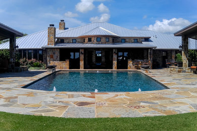 Diseño de piscina con fuente alargada tradicional grande rectangular en patio trasero con adoquines de piedra natural