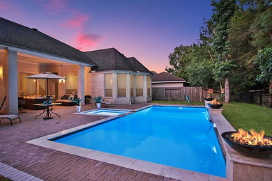 Esempio di una grande piscina monocorsia design rettangolare dietro casa con fontane e pavimentazioni in mattoni