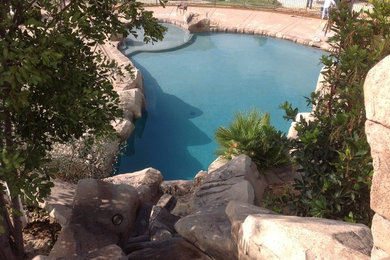 Diseño de piscina con fuente natural costera grande a medida en patio trasero con adoquines de piedra natural
