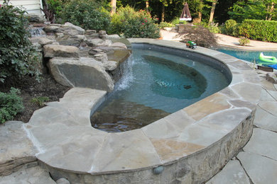 Modelo de piscinas y jacuzzis naturales clásicos renovados de tamaño medio a medida en patio trasero con adoquines de piedra natural