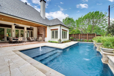 This is an example of a medium sized traditional back l-shaped swimming pool in Dallas with a water feature and concrete slabs.