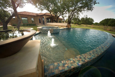 Idee per una piscina a sfioro infinito mediterranea a "C" di medie dimensioni e dietro casa con fontane e pavimentazioni in pietra naturale