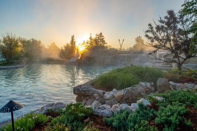 Ispirazione per un'ampia piscina naturale country personalizzata dietro casa con un acquascivolo e pavimentazioni in pietra naturale