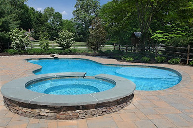 Modelo de piscinas y jacuzzis clásicos de tamaño medio a medida en patio trasero con adoquines de hormigón