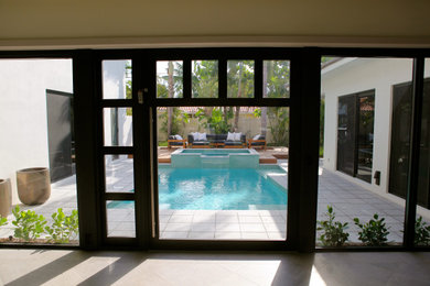 Large island style courtyard concrete paver and rectangular infinity hot tub photo in Miami