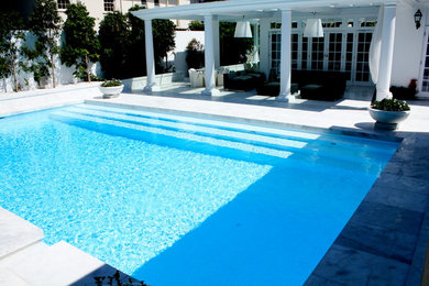 Ejemplo de piscina mediterránea grande rectangular en patio trasero con adoquines de piedra natural