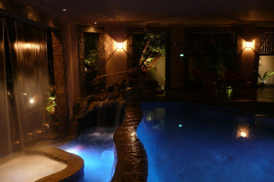Inspiration for a mid-sized tropical backyard stamped concrete and custom-shaped infinity hot tub remodel in Los Angeles