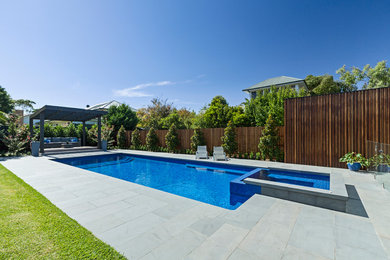 На фото: большой спортивный, прямоугольный бассейн на заднем дворе в современном стиле с домиком у бассейна и покрытием из каменной брусчатки с