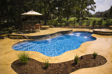 Modelo de piscina con fuente alargada de tamaño medio a medida en patio trasero con adoquines de hormigón
