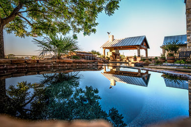 Immagine di un'ampia piscina naturale tropicale personalizzata dietro casa con una vasca idromassaggio e pavimentazioni in pietra naturale