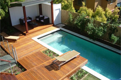 Foto de piscina alargada actual grande rectangular en patio trasero con entablado