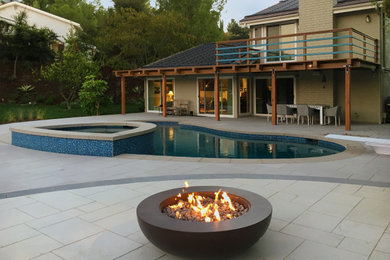 Design ideas for a large contemporary back custom shaped lengths hot tub with concrete paving.