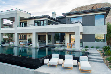 Diseño de piscina infinita contemporánea grande en forma de L en patio trasero con losas de hormigón