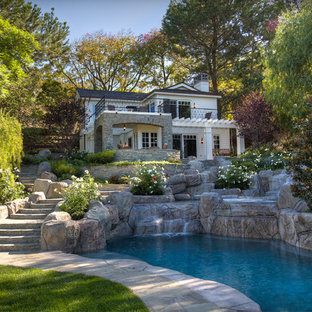 This is an example of a large traditional backyard custom-shaped natural pool in Orange County with natural stone pavers.