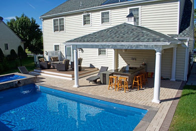 Foto de piscina tradicional grande rectangular en patio trasero con adoquines de hormigón