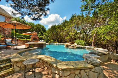 Elegant backyard stone and custom-shaped hot tub photo in Austin