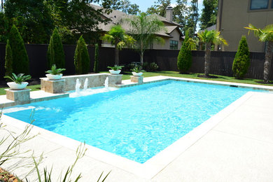 Foto de piscina con fuente alargada tradicional renovada grande rectangular en patio trasero con losas de hormigón