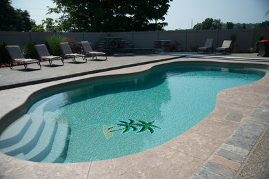 Photo of a medium sized modern back custom shaped swimming pool in Other with stamped concrete.
