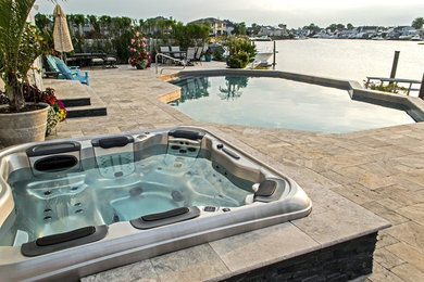 Example of a mid-sized classic backyard stone and custom-shaped hot tub design in New York