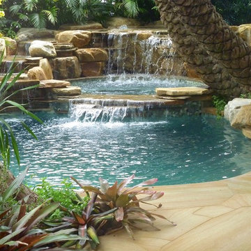 Tropical backyard pool waterfall into jacuzzi