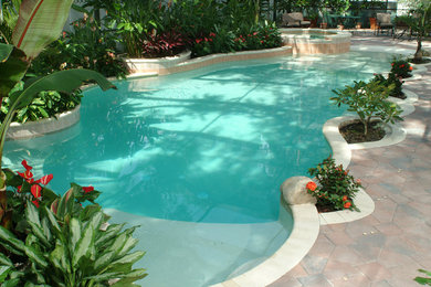 Modelo de piscinas y jacuzzis exóticos de tamaño medio a medida en patio trasero con adoquines de hormigón