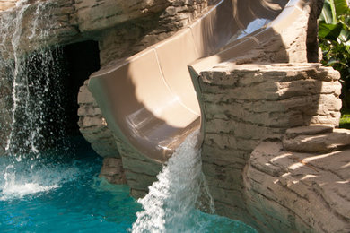 Ispirazione per un'ampia piscina tropicale personalizzata con pavimentazioni in cemento e una vasca idromassaggio