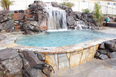 Imagen de piscina con fuente natural exótica a medida en patio trasero