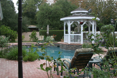 Mid-sized elegant backyard stone and custom-shaped pool photo in Los Angeles