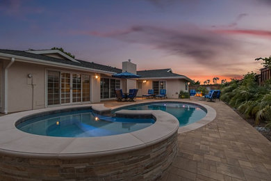 Example of a mid-sized transitional backyard stone and round lap hot tub design in Orange County