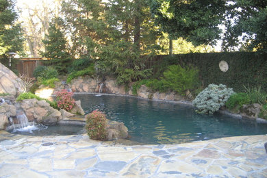 Ejemplo de piscina con tobogán a medida con adoquines de piedra natural