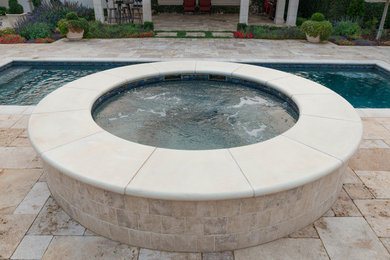 Modelo de piscinas y jacuzzis alargados rectangulares en patio trasero con adoquines de piedra natural