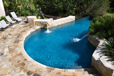 Diseño de piscina con fuente infinita mediterránea grande a medida en patio trasero con adoquines de piedra natural