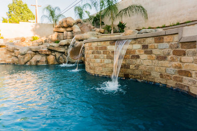 Inspiration for a mid-sized tropical backyard stamped concrete and custom-shaped natural water slide remodel in Los Angeles