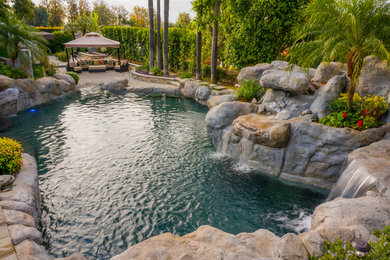 Example of a large classic backyard concrete paver and custom-shaped natural water slide design in Los Angeles