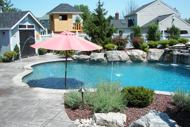 Elegant backyard stamped concrete and custom-shaped natural pool photo in Philadelphia