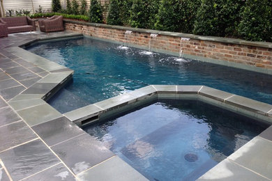 Ispirazione per una piscina monocorsia tradizionale rettangolare di medie dimensioni e dietro casa con una vasca idromassaggio e pavimentazioni in pietra naturale