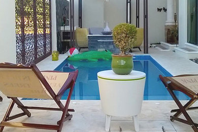 Ejemplo de casa de la piscina y piscina actual rectangular en patio con adoquines de piedra natural