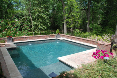Modelo de piscina con fuente actual grande rectangular en patio trasero con adoquines de ladrillo