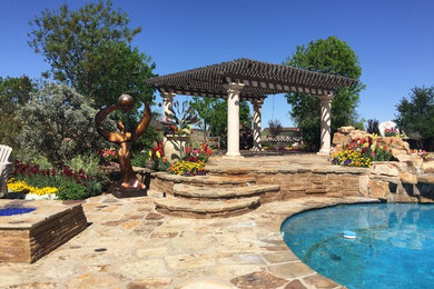 Foto de piscina tradicional grande a medida en patio trasero con adoquines de piedra natural