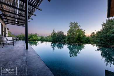 Pool - mid-sized modern backyard stone and custom-shaped infinity pool idea in Nashville