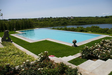 Foto de piscina infinita actual grande a medida en patio trasero con adoquines de piedra natural