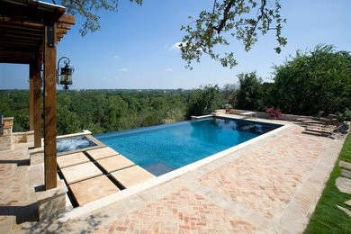 На фото: прямоугольный бассейн-инфинити среднего размера на заднем дворе в классическом стиле с джакузи и мощением клинкерной брусчаткой с