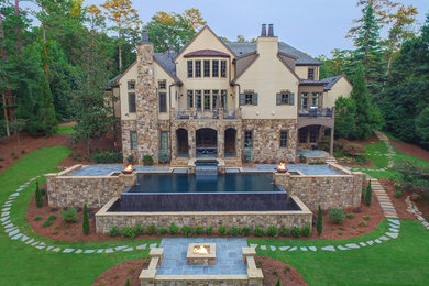Inspiration for a large world-inspired back custom shaped infinity swimming pool in Atlanta with a water feature and natural stone paving.