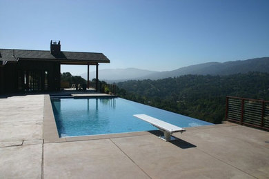 Пример оригинального дизайна: прямоугольный бассейн-инфинити среднего размера на заднем дворе в современном стиле с джакузи и покрытием из декоративного бетона