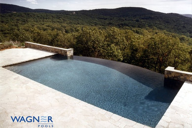 Large traditional back rectangular infinity swimming pool in New York with a water feature and natural stone paving.