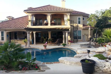 Mid-sized tuscan backyard concrete and custom-shaped lap pool photo in Austin