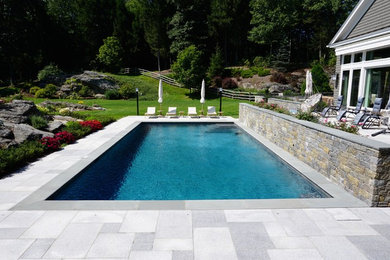 Example of a mid-sized minimalist backyard stone and rectangular lap pool design in New York